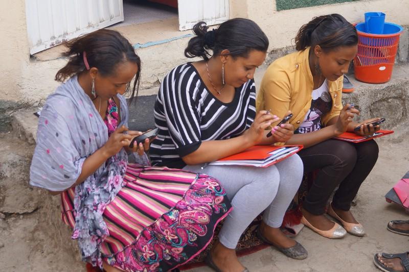 Trois femmes font un pas en avant en regardant des téléphones portables